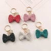Four sparkling rhinestone bow keychains in red, pink, black, and teal.
