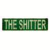 A vintage green metal tin sign with the text THE SHITTER in distressed white lettering.