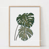 Botanical Philodendron canvas wall art featuring large green leaves framed in light wood.