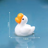 Sculpture de canard en résine blanche avec bec orange flottant sur une surface bleue.