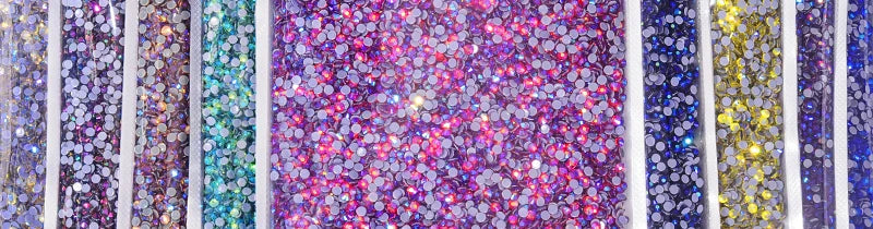 A close-up of hotfix glass rhinestones in various colors and sizes, including purple, blue, green, and yellow.