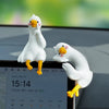 Deux figurines de canards blancs avec des pattes jaunes sont posées sur un écran de smartphone.