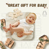 A baby smiling on a milestone card with a bear design, surrounded by wooden gift boxes.