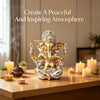 A golden Ganesha statue figurine of the Hindu elephant god placed on a wooden table with lit candles.