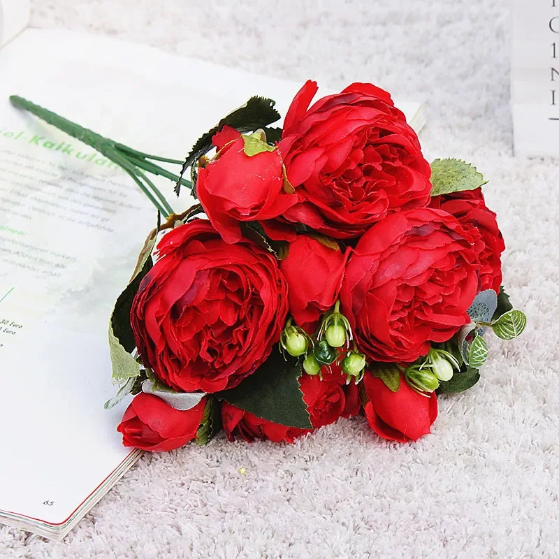A vibrant bouquet of red silk roses and peonies used for home and event decoration.