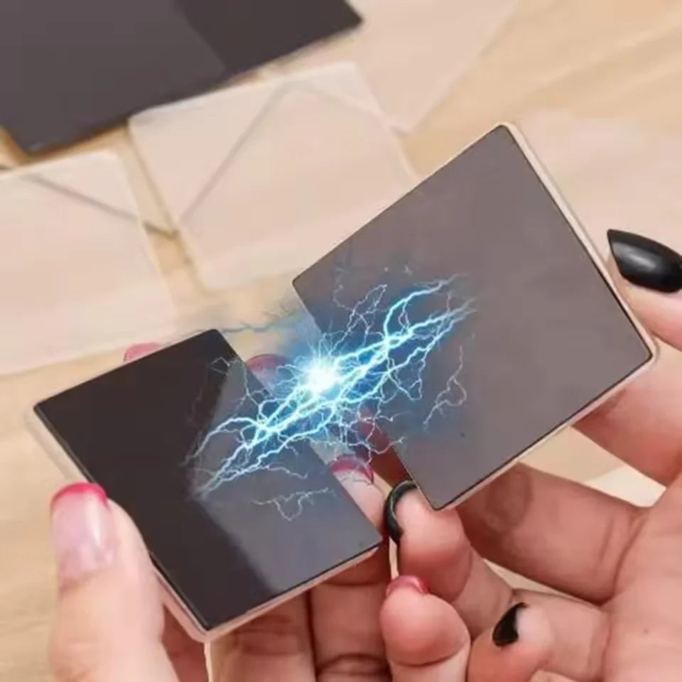 Hands hold a black acrylic fridge magnet with blue electrical lightning effects.