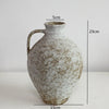 A vintage dual-sided ceramic vase with a rounded body and narrow neck, showing speckled off-white and brown tones.