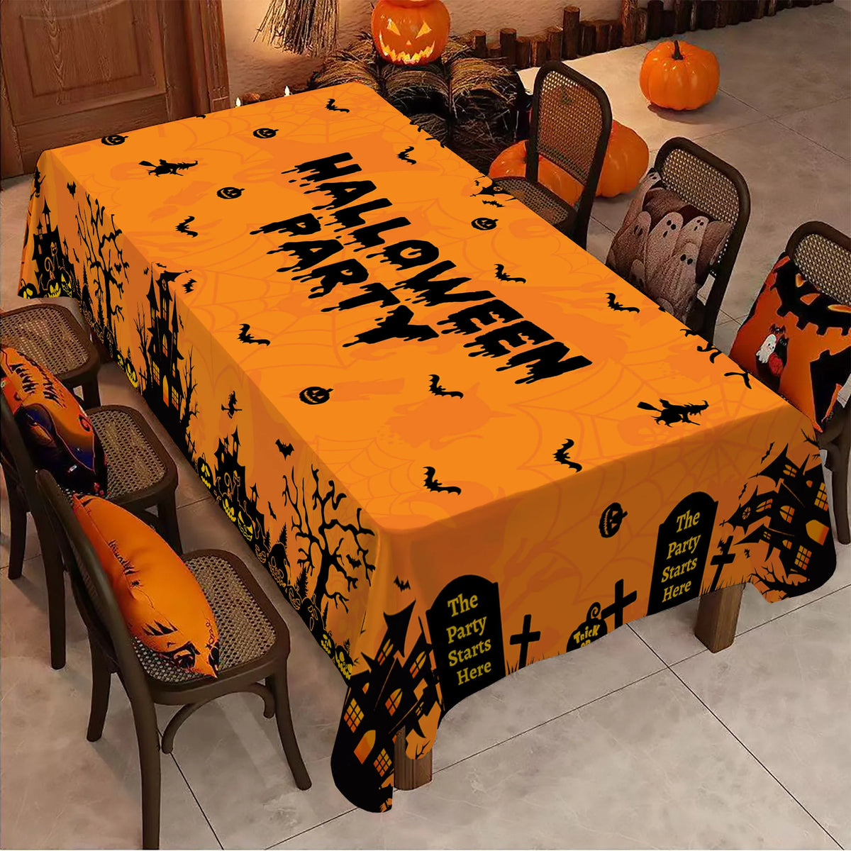 An orange rectangle tablecloth patterned with black bats and ghosts set on a dining table.