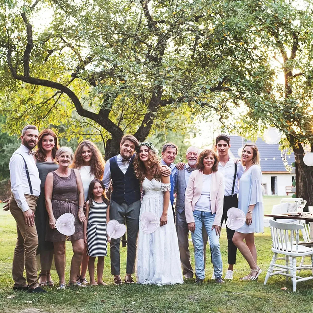 A group of people posing outdoors with heart-shaped paper folding fans.