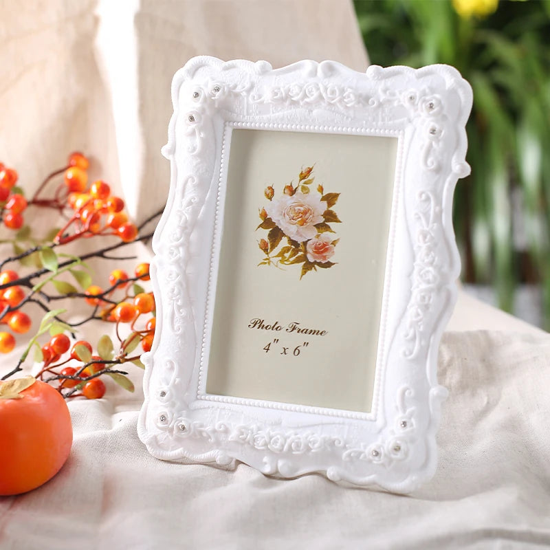 White embossed resin photo frame with a floral design displayed on a light fabric.