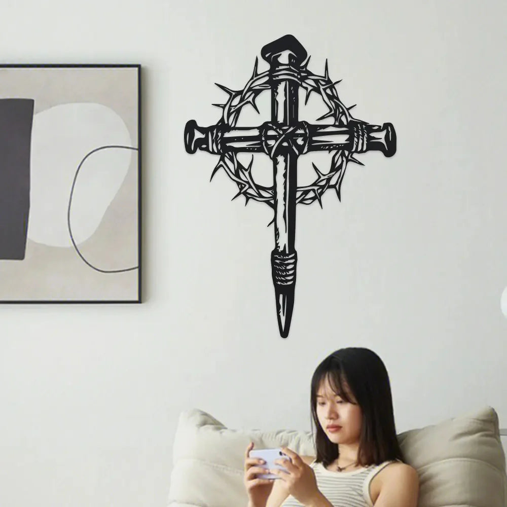 Black metal cross wall art with thorn details mounted on a white wall.