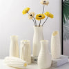 A collection of white Nordic minimalist plastic vases of varying heights and shapes for fresh flowers.