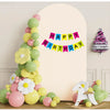 Arreglo floral vertical de globos rosas y verdes con una pancarta de cumpleaños feliz contra una pared clara.