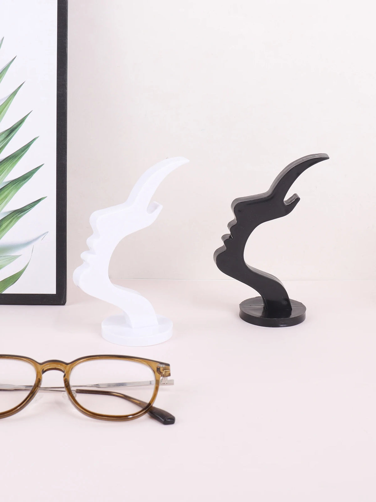 A pair of minimalist side face glasses holders in white and black displayed on a white surface.