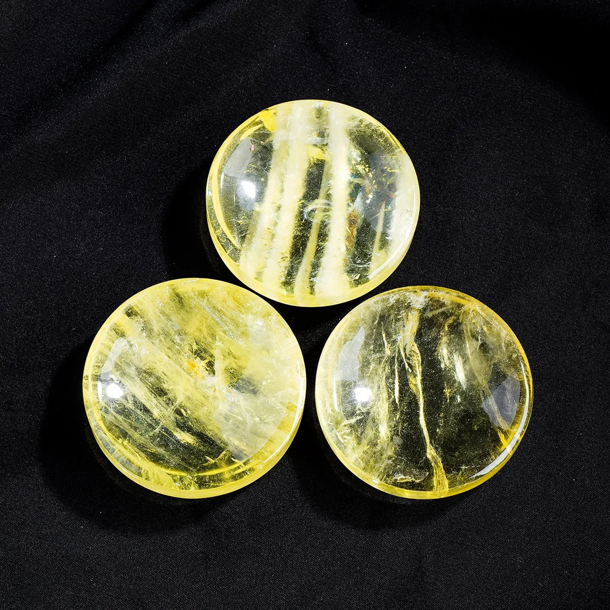 Three polished yellow citrine crystal bowls with natural veining set against a black background