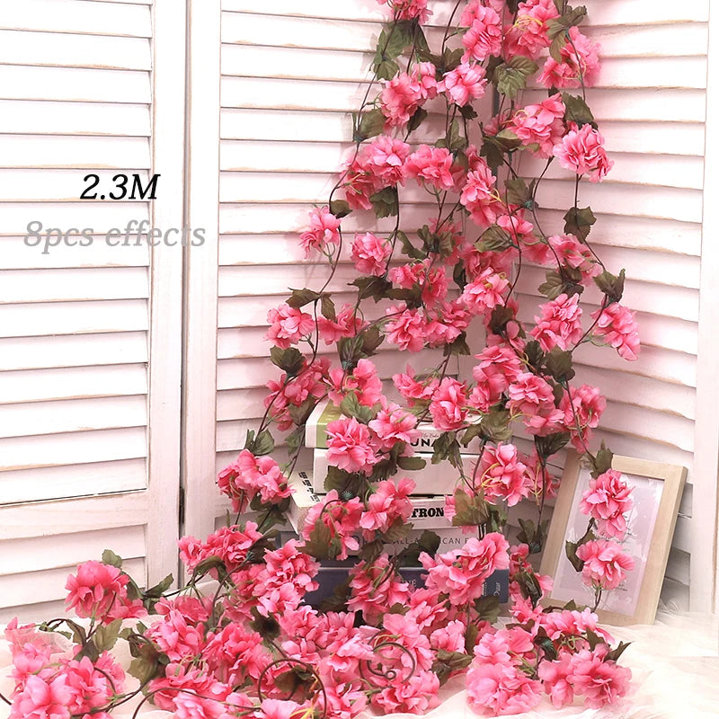 A long, cascading garland of pink artificial sakura flowers displayed against a white wooden background.