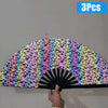 Three folding bamboo hand fans with a colorful geometric pattern displayed against a white wall.
