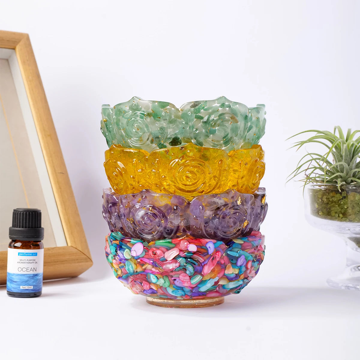 A stack of natural crystal lotus bowls in various shades of green, yellow, and purple on a white background.