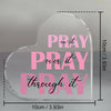 A clear acrylic heart-shaped sign with the text Pray on it Pray over it and Pray through it printed in pink script.