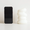 A black smartphone next to a white, spiral-shaped decorative vase.