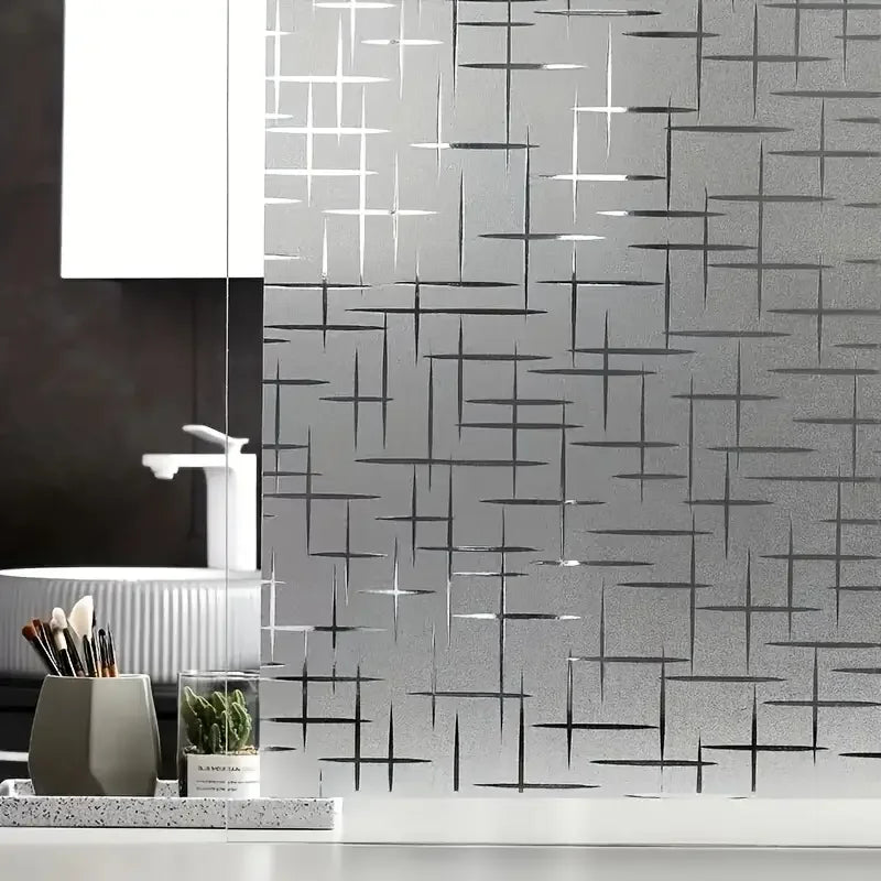 A close-up of frosted electrostatic window film applied to glass, featuring a geometric pattern on a kitchen backsplash.