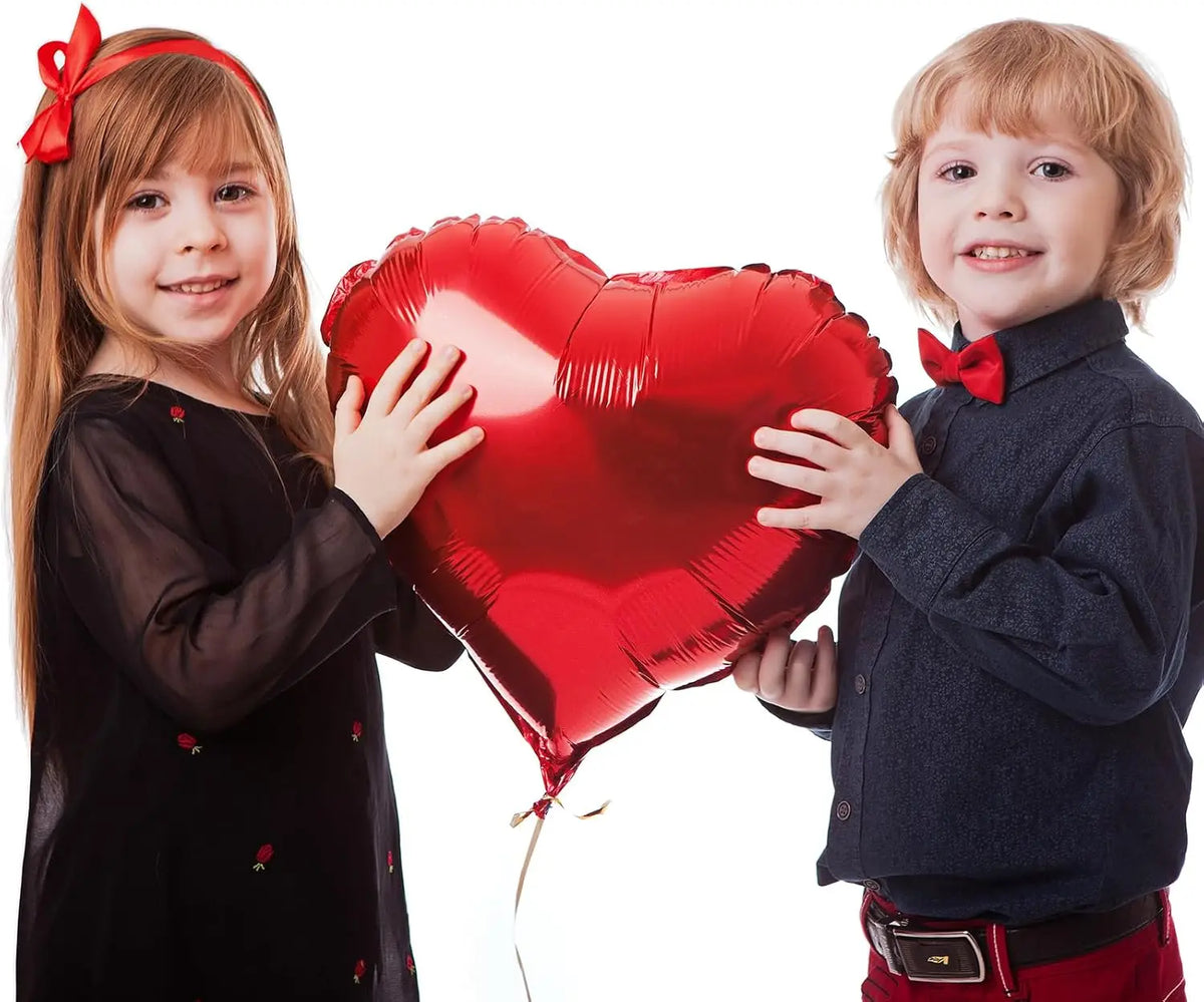 Two young children holding a large red heart foil balloon for Valentine's Day decorations