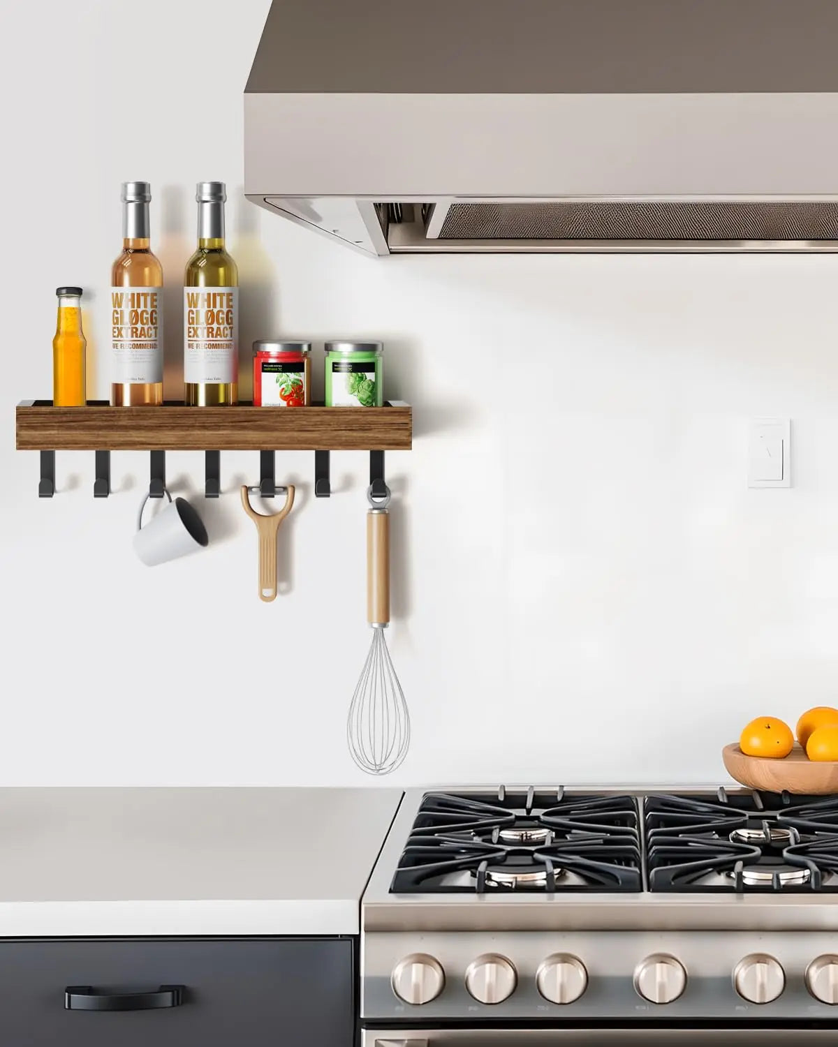 Rustic wooden floating shelf with hooks displaying olive oils and a whisk above a stovetop.