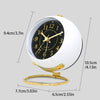 A white minimalist Nordic alarm clock with a black face and gold accents, shown from above.
