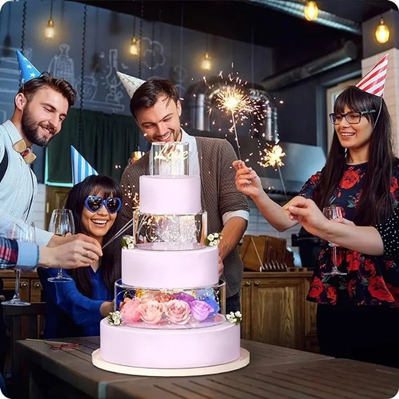 A woman holds a tiered pink cake with gold accents in front of a man and another woman in a kitchen setting.