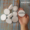 A hand holds several white polystyrene foam balls for crafting and decorating on a wooden surface.