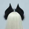 A black bat simulation headpiece with feathery ears is displayed on a white wig.