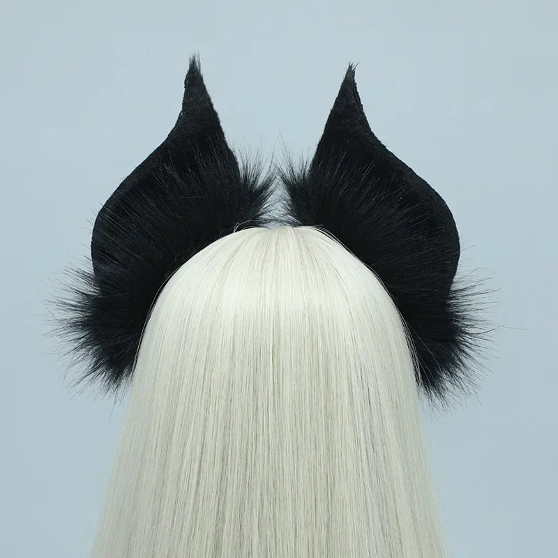 A black bat simulation headpiece with feathery ears is displayed on a white wig.