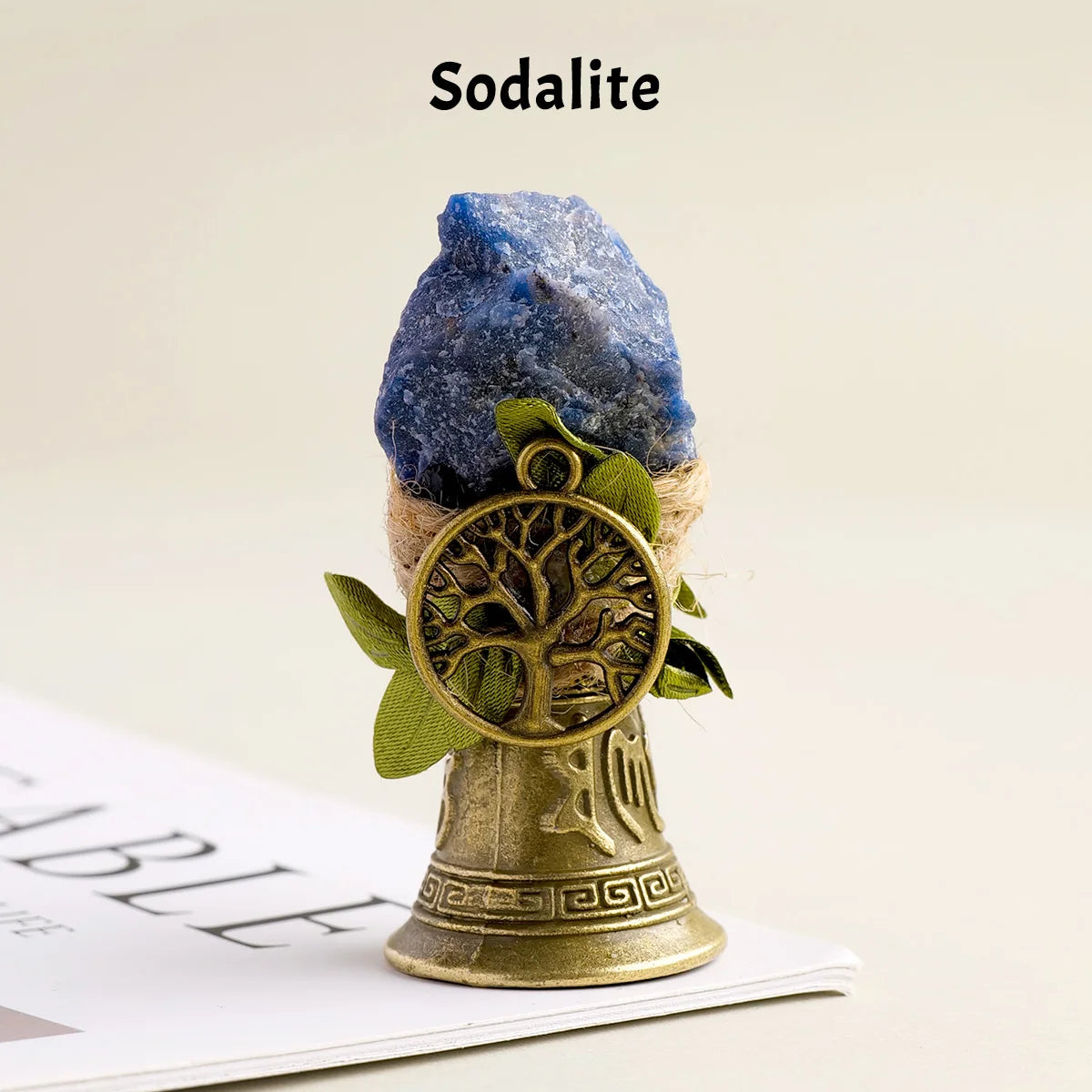 A natural crystal sodalite stone is mounted on a brass bell with a copper finish.
