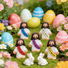 A collection of colorful mini rubber Jesus figurines in various Easter egg colors and pinks set in a garden with flowers.