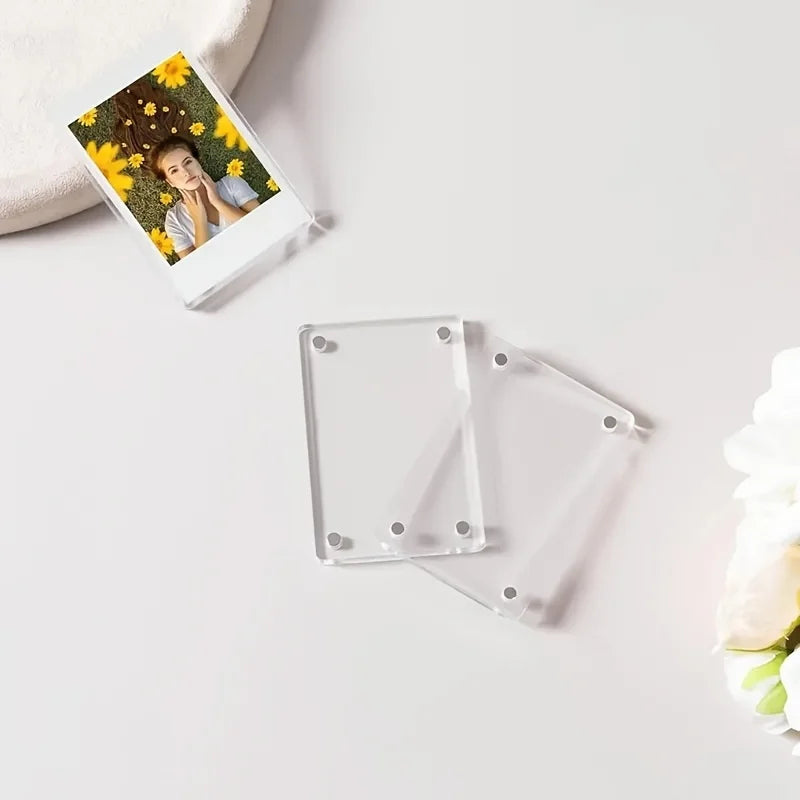 A clear magnetic acrylic picture frame with a photo of a person surrounded by yellow flowers is shown on a white surface.