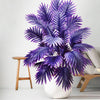 A vibrant purple artificial palm tree with detailed silk leaves displayed in a white pot.
