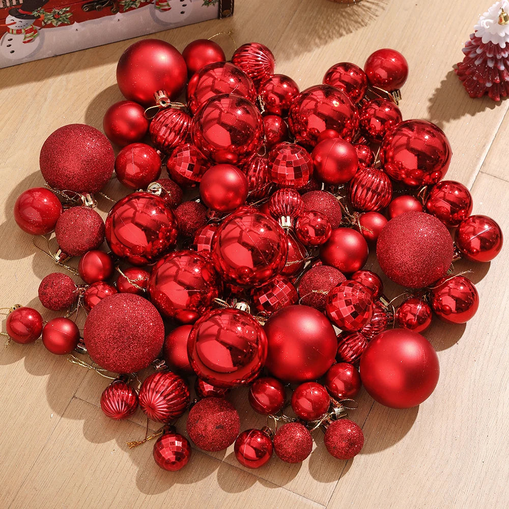 A collection of assorted shiny red and gold Christmas tree ornaments and pendants scattered on a light wooden surface.