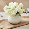 A bouquet of white artificial foam roses in a white vase on a beige linen cloth.
