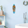 A wooden wall decor sign shaped like a surfboard featuring a tropical scene and the text 'Living the Dream'