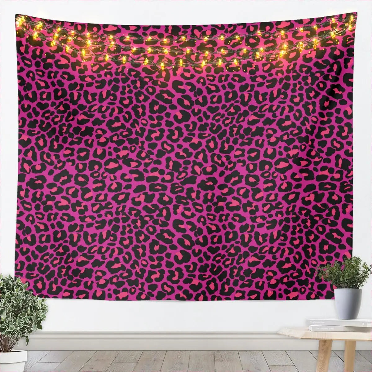 A vibrant pink and black leopard print tapestry wall hanging with warm string lights.