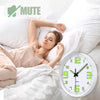 Une femme dort dans son lit à côté d'une horloge murale en plastique lumineux moderne.