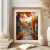 A framed canvas painting depicting an autumn field landscape with vibrant orange and red foliage on a cobblestone path.