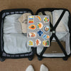 A pack of watercolor food and fruit stickers is displayed inside a black storage basket with soft fabric items.