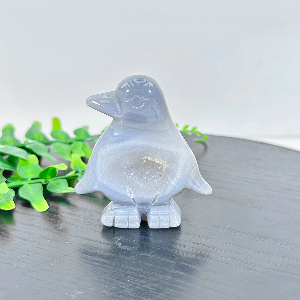 A smooth, translucent gray agate crystal figurine of a bird sitting on a dark surface.