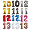 A collection of gold, silver, and black helium foil number balloons for a birthday party.