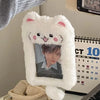 A white fluffy cat plush holder with a photo inside, displayed next to a calendar.