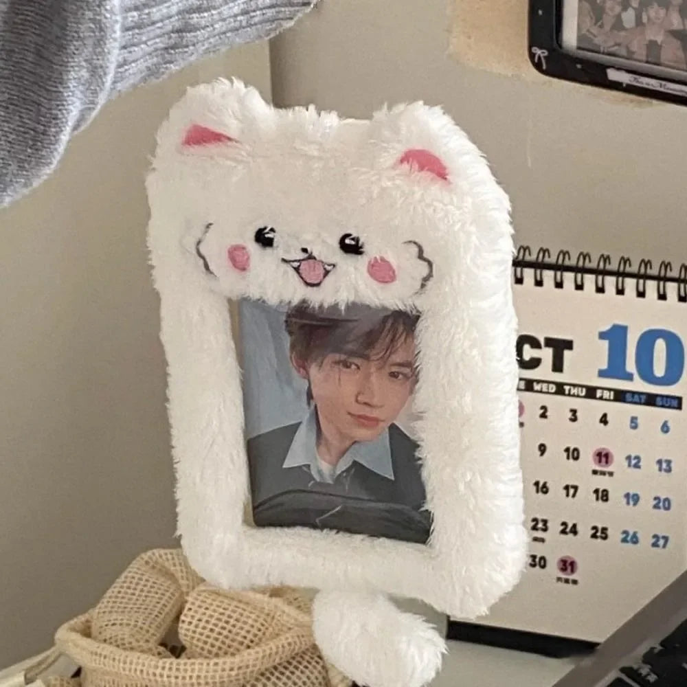 A white fluffy cat plush holder with a photo inside, displayed next to a calendar.