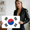 A woman holds a vintage Taegeukgi metal wall plaque against a white background.