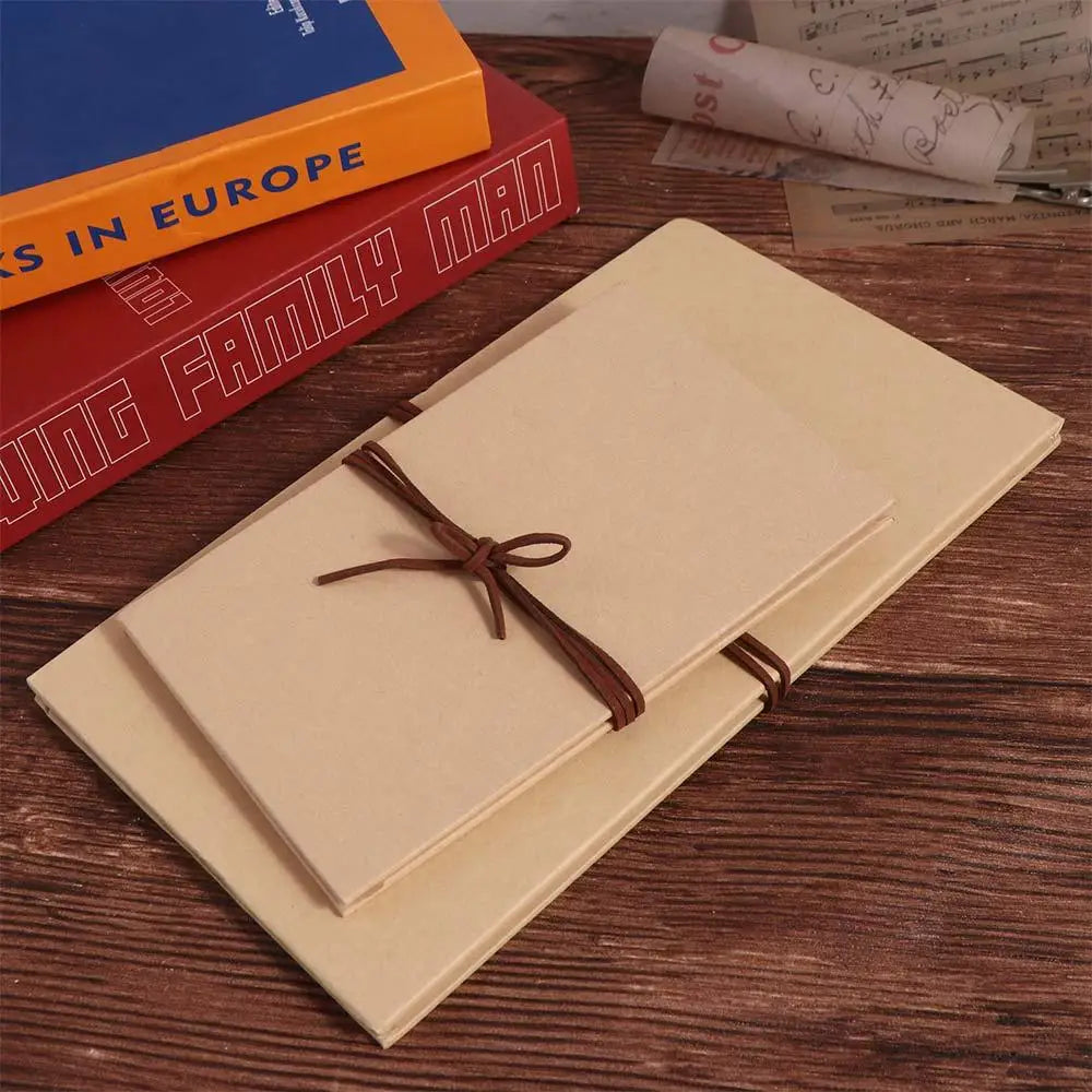 A handcrafted accordion photo album with light beige pages and a brown leather tie resting on a wooden surface.