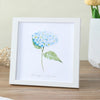 A white photo frame displays a watercolor illustration of blue hydrangeas on a white background.